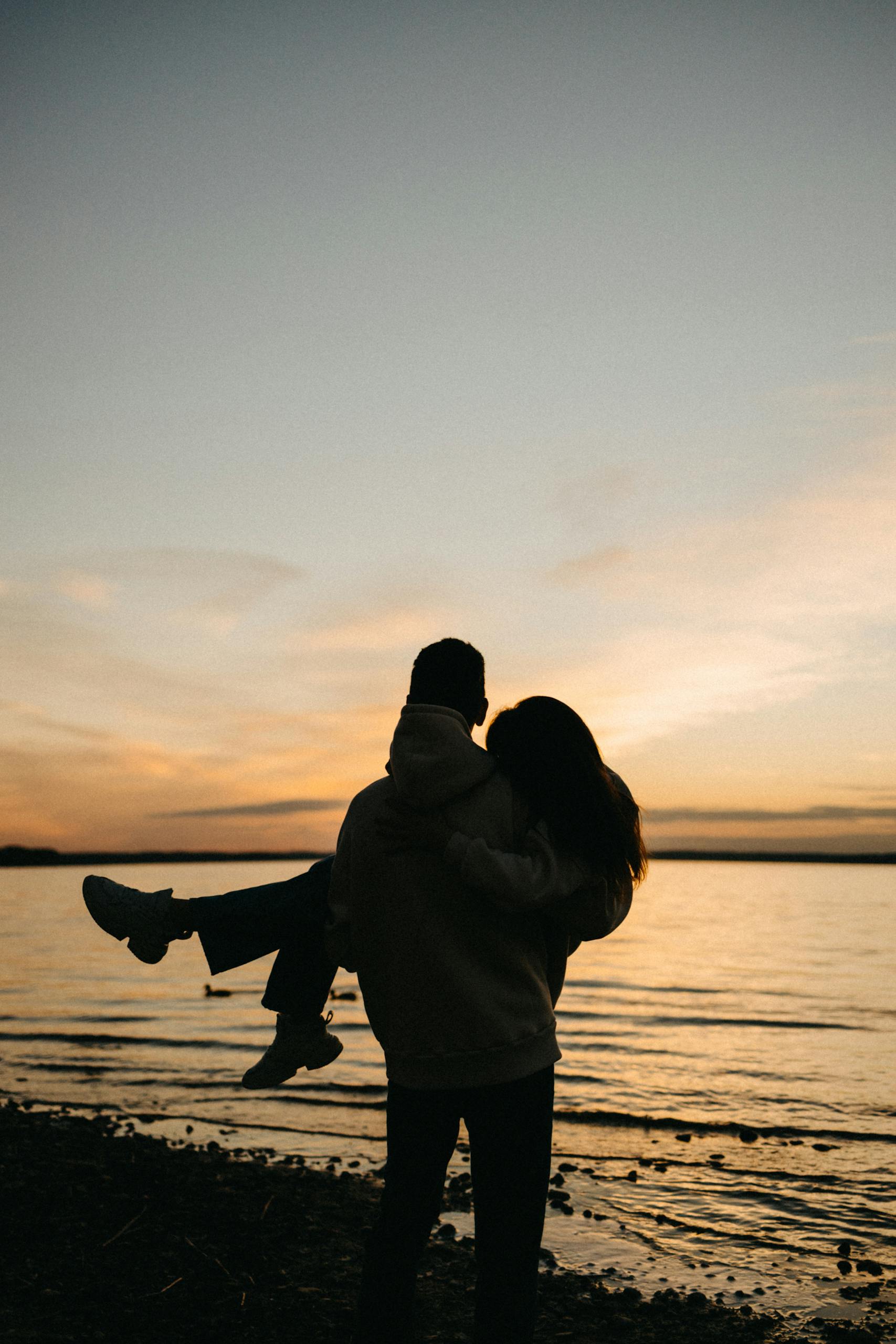 A romantic silhouette of a couple at the beach during a serene sunset, embracing love and tranquility.